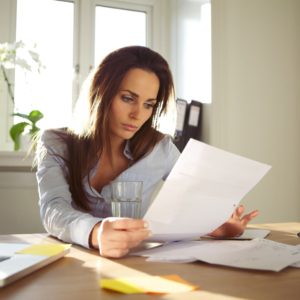 Woman working on Laptop looking at paperwork