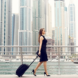 Woman wearing black dress with a suitcase in city